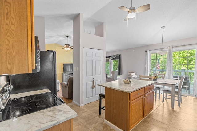 kitchen featuring light stone counters, stove, pendant lighting, vaulted ceiling, and a kitchen island