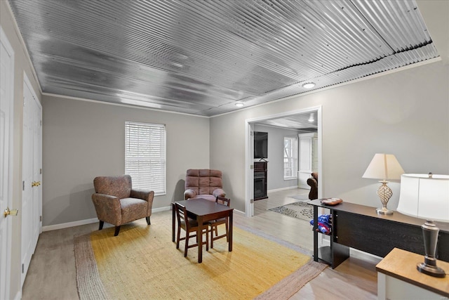 sitting room featuring light wood-type flooring, crown molding, and wood ceiling