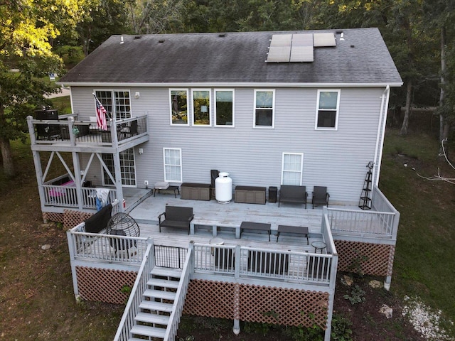 rear view of property featuring solar panels, a deck, and an outdoor hangout area