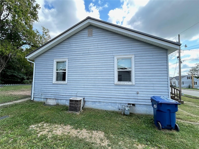 view of side of home featuring cooling unit and a lawn