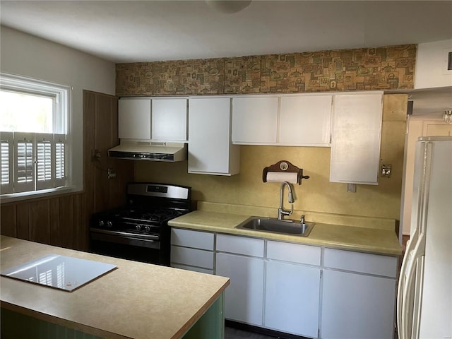 kitchen with white cabinetry, sink, white refrigerator, and black gas stove