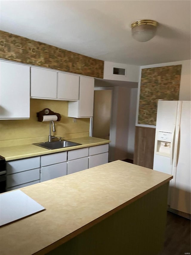 kitchen featuring white cabinetry, a center island, white refrigerator with ice dispenser, and sink