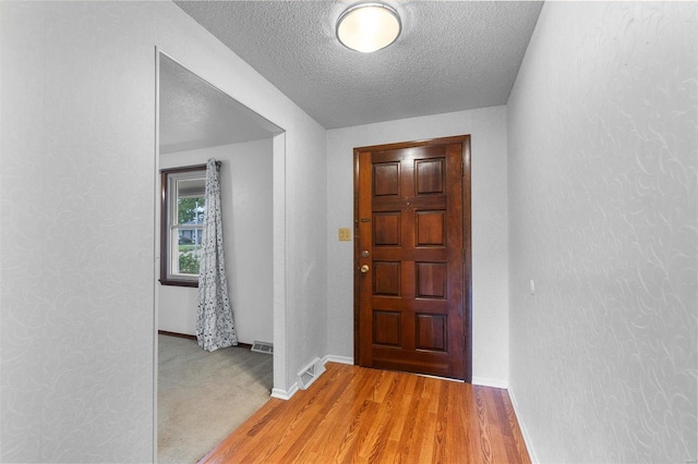 foyer entrance with a textured ceiling and wood-type flooring