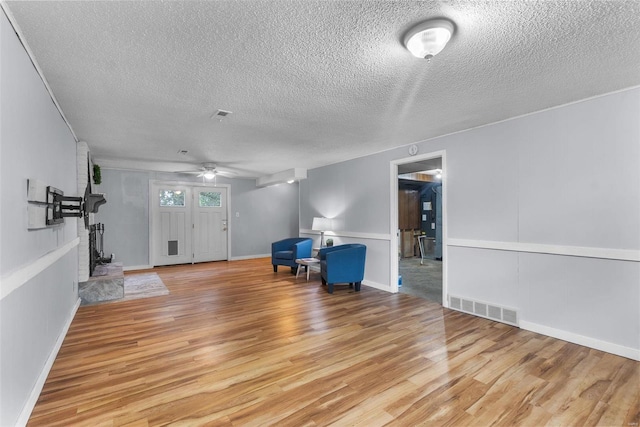 unfurnished living room with a textured ceiling, ceiling fan, and light hardwood / wood-style flooring