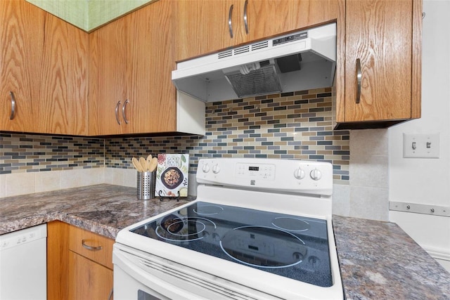 kitchen featuring dark stone countertops, white appliances, and backsplash