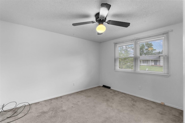 empty room featuring a textured ceiling, light carpet, and ceiling fan