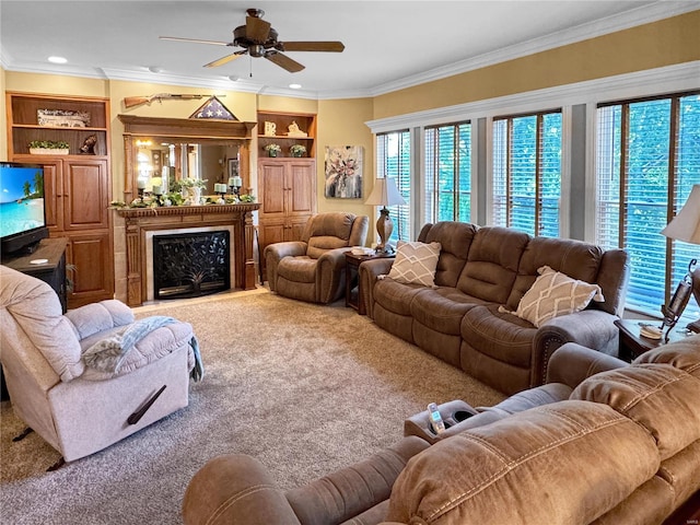 living room featuring crown molding, a premium fireplace, ceiling fan, and carpet floors