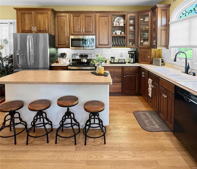 kitchen with light hardwood / wood-style flooring, appliances with stainless steel finishes, a kitchen bar, and sink