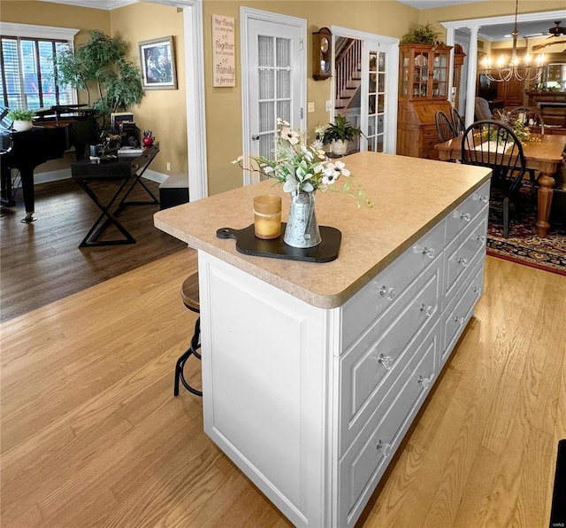 kitchen with a center island, light hardwood / wood-style flooring, decorative light fixtures, a kitchen bar, and ornamental molding