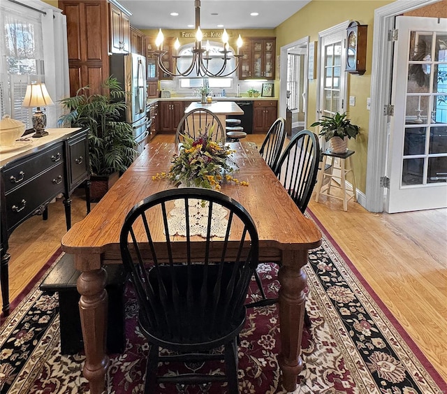 dining space with light wood-type flooring and a notable chandelier