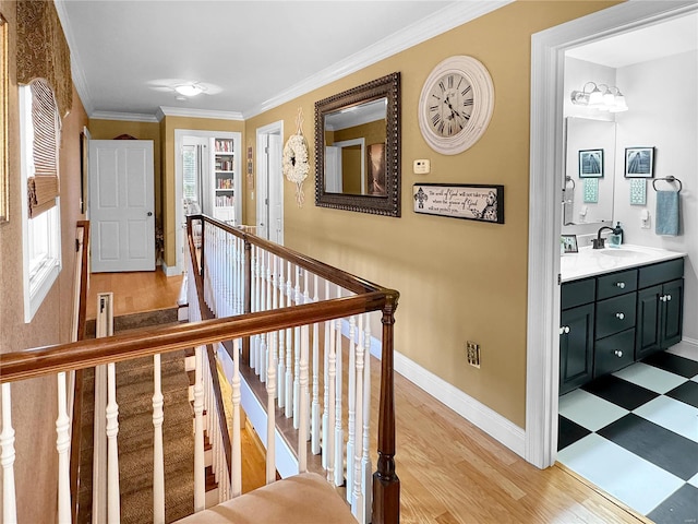 hall with light wood-type flooring, ornamental molding, and sink