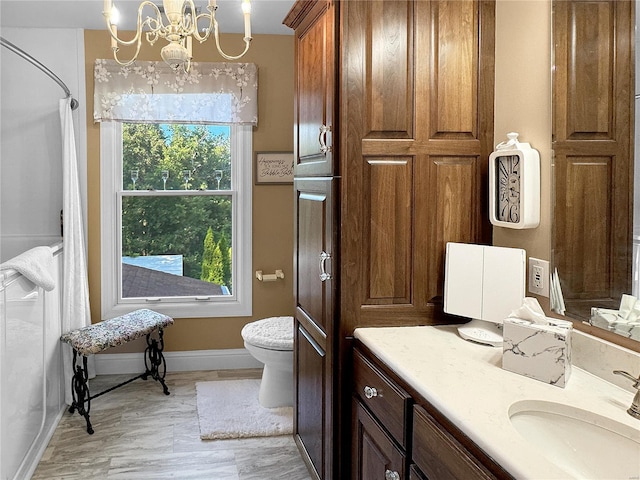 bathroom with vanity, toilet, a healthy amount of sunlight, and a chandelier