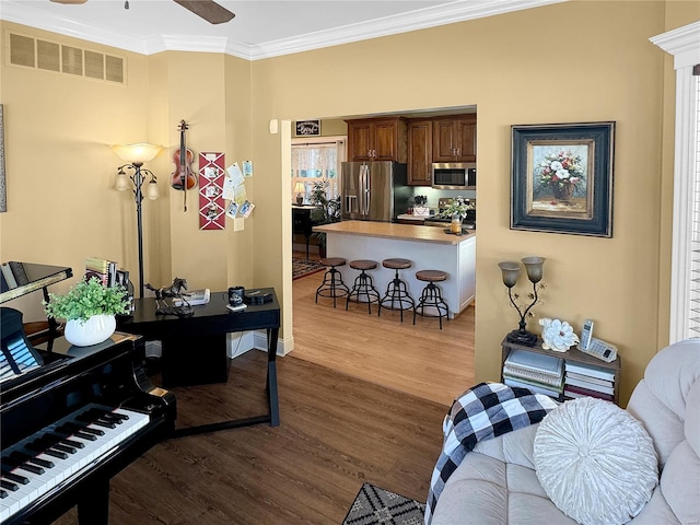 living room featuring light wood-type flooring, ceiling fan, and ornamental molding