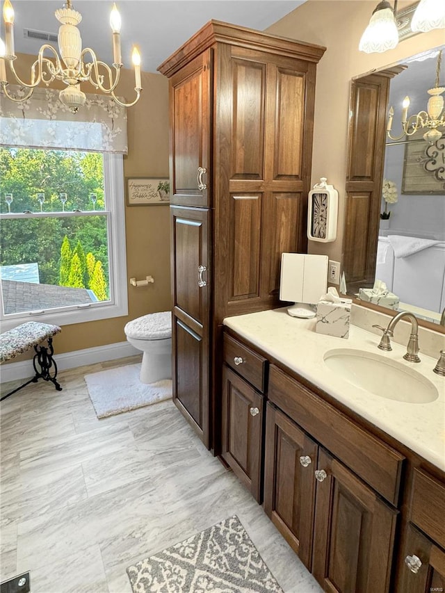 bathroom with toilet, a notable chandelier, and vanity