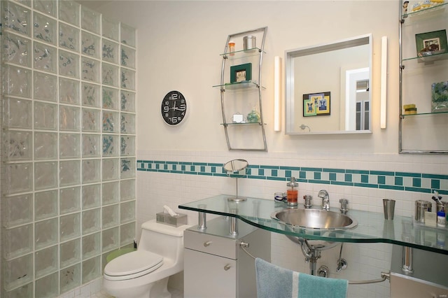 bathroom featuring toilet, tile walls, and sink