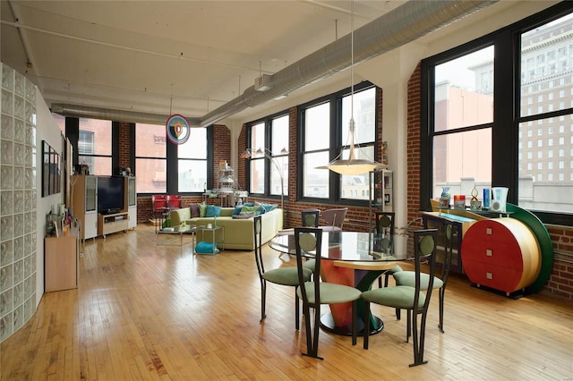 dining room featuring plenty of natural light, brick wall, and light hardwood / wood-style flooring