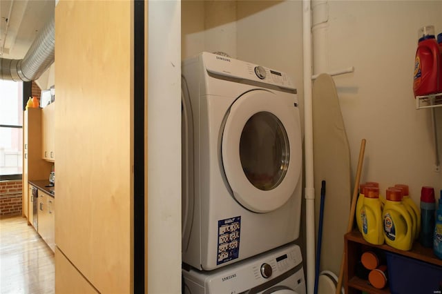 laundry area with light hardwood / wood-style floors and stacked washer / drying machine