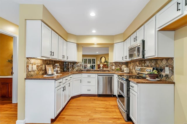 kitchen with light wood-type flooring, stainless steel appliances, and white cabinets