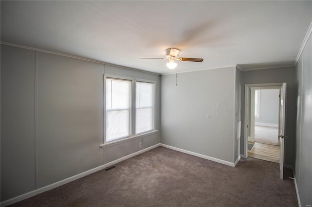 spare room featuring crown molding, dark carpet, and ceiling fan