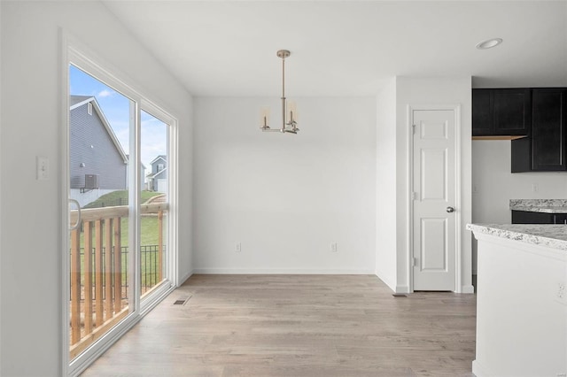 unfurnished dining area featuring light hardwood / wood-style flooring and a chandelier