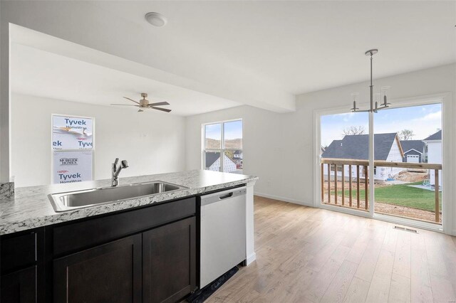 kitchen featuring light stone countertops, ceiling fan with notable chandelier, dishwasher, light hardwood / wood-style flooring, and sink