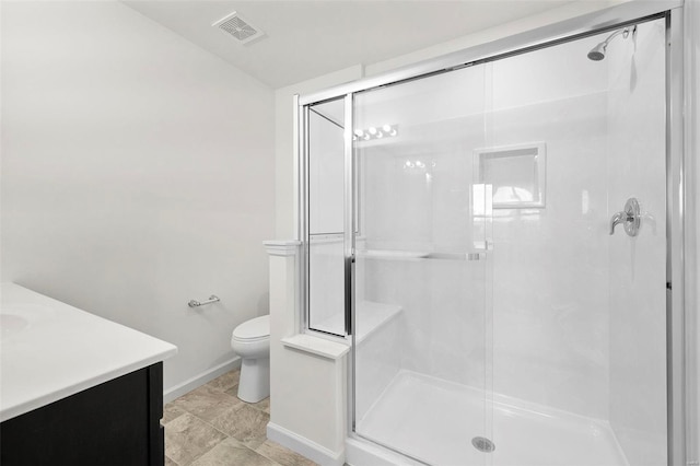 bathroom featuring a shower with door, vanity, and toilet