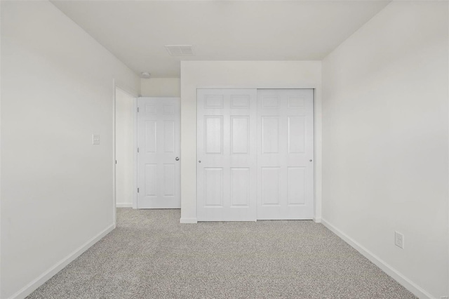 unfurnished bedroom featuring light carpet and a closet