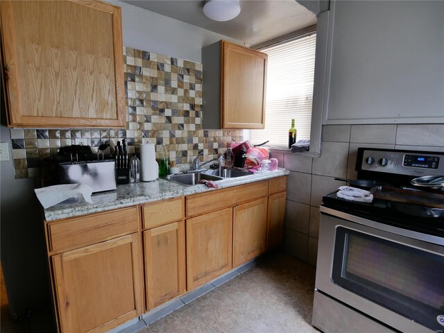 kitchen featuring backsplash, light tile patterned floors, light stone countertops, sink, and stove