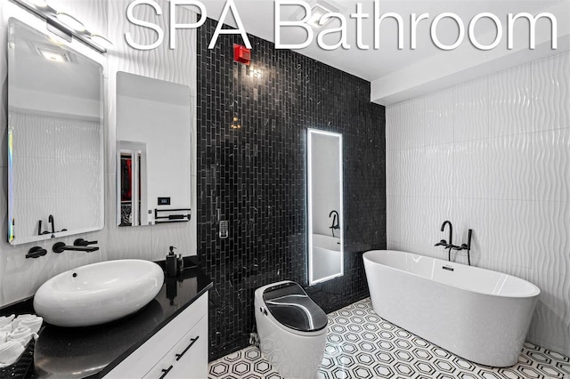 bathroom with tile walls, tile patterned flooring, a bathtub, and vanity