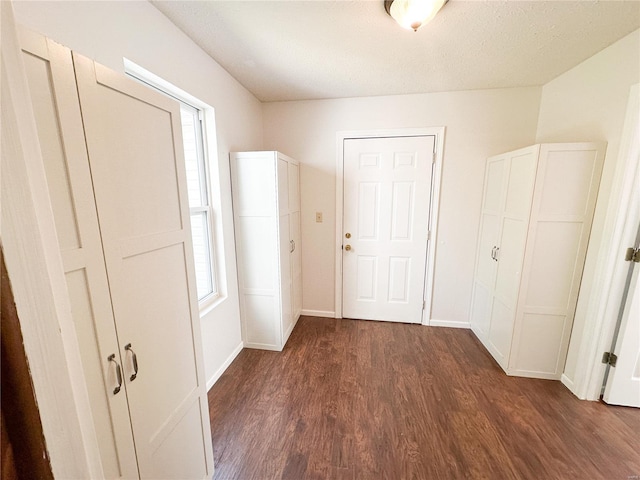 corridor with dark hardwood / wood-style flooring and a textured ceiling