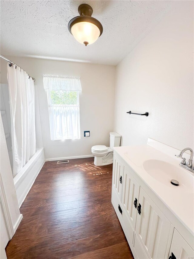 full bathroom with toilet, vanity, a textured ceiling, shower / bath combo, and hardwood / wood-style flooring