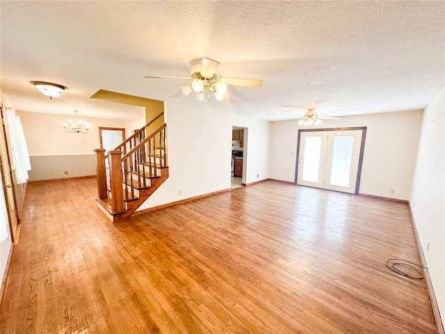 unfurnished living room with ceiling fan with notable chandelier, a textured ceiling, and light hardwood / wood-style floors