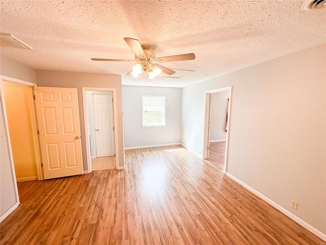 unfurnished bedroom featuring hardwood / wood-style floors, ceiling fan, and a textured ceiling