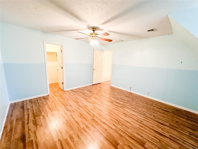 interior space featuring lofted ceiling, ceiling fan, light hardwood / wood-style floors, and a textured ceiling