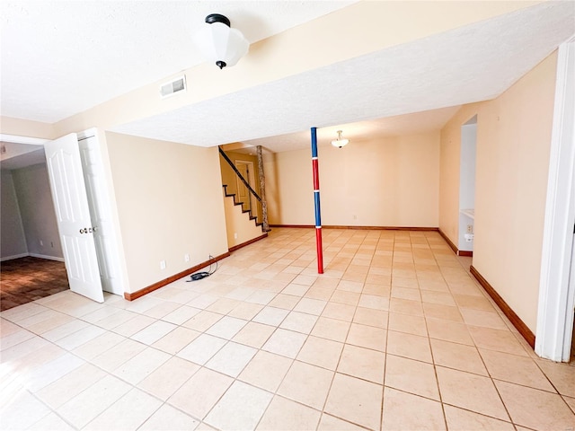 basement featuring light tile patterned floors and a textured ceiling