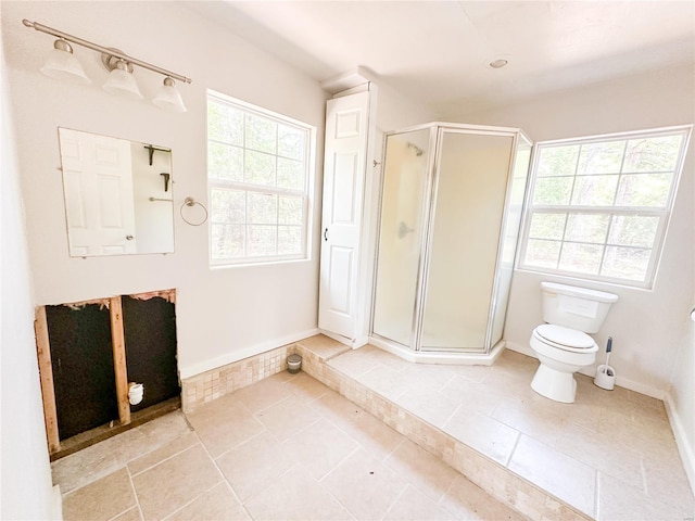 bathroom with a healthy amount of sunlight, toilet, tile patterned floors, and walk in shower