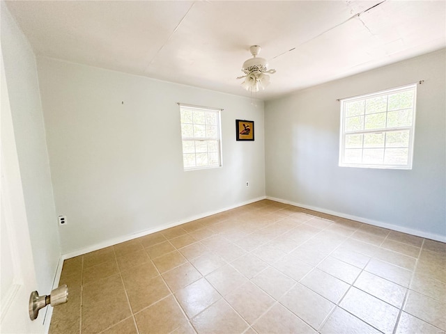 empty room featuring ceiling fan, light tile patterned floors, and a healthy amount of sunlight