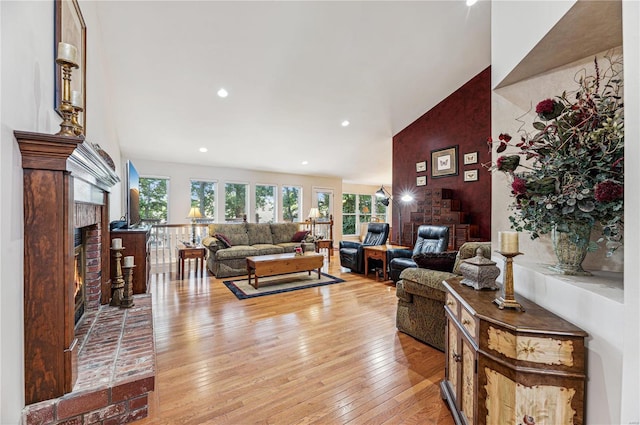 living room featuring light hardwood / wood-style floors, a fireplace, and vaulted ceiling