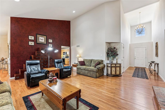 living room with light hardwood / wood-style floors, a notable chandelier, and high vaulted ceiling