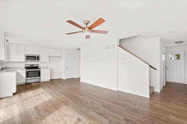 kitchen featuring hardwood / wood-style floors, stainless steel appliances, sink, ceiling fan, and white cabinets