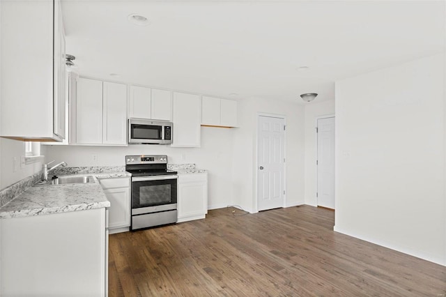 kitchen with white cabinetry, stainless steel appliances, dark hardwood / wood-style flooring, sink, and light stone countertops