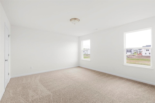 unfurnished room featuring light colored carpet and baseboards