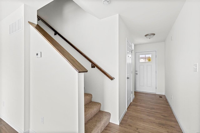 foyer entrance with visible vents, stairs, baseboards, and wood finished floors