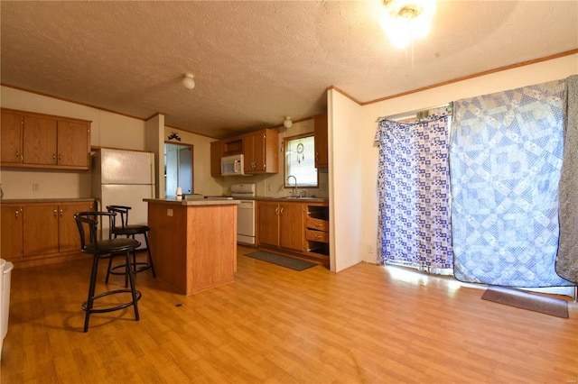 kitchen featuring white appliances, light hardwood / wood-style flooring, a center island, and a kitchen breakfast bar