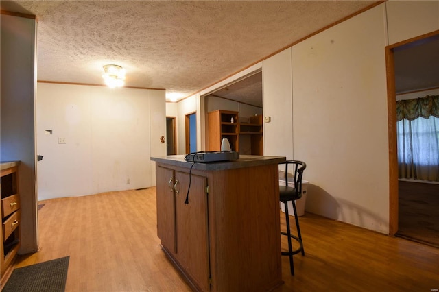 kitchen with a breakfast bar area, light hardwood / wood-style flooring, and a textured ceiling