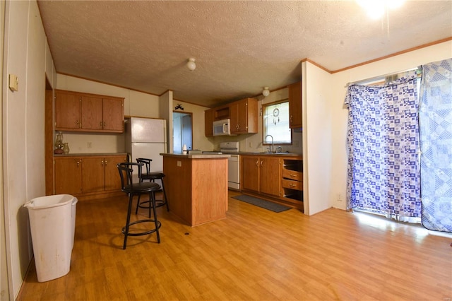 kitchen with light wood-type flooring, white appliances, a center island, and a breakfast bar