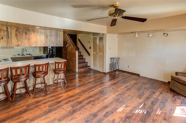 kitchen with sink, a kitchen bar, kitchen peninsula, ceiling fan, and dark wood-type flooring