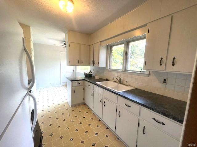 kitchen with white cabinets, white refrigerator, sink, and decorative backsplash