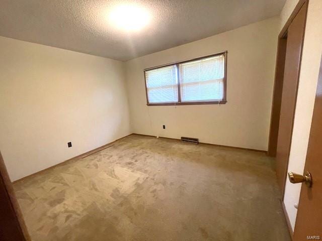 carpeted empty room with a textured ceiling