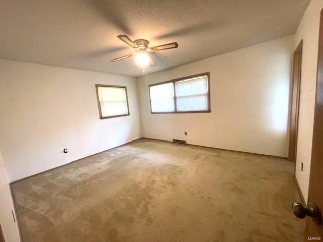 carpeted empty room with a textured ceiling and ceiling fan